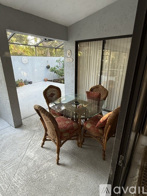 A glass table with four chairs is in a room with a glass door.