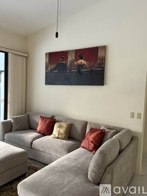 A living room with a grey couch and a painting on the wall.