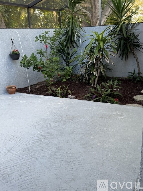 A white wall with a hanging planter and a pot on the ground.