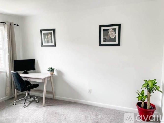 A room with a desk, chair, and two pictures on the wall.