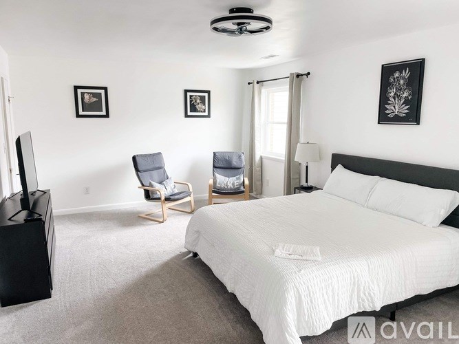 A bedroom with a large bed, a chair, and a television.
