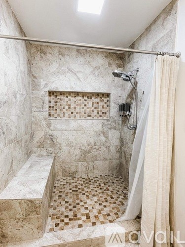 A bathroom with a marble tile shower and bench.