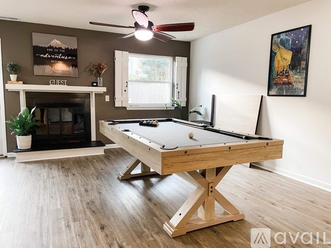 A pool table in a room with a fireplace and a painting on the wall.