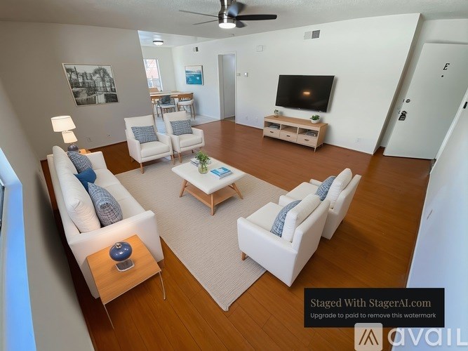 A living room with a white couch, a coffee table, and a television.