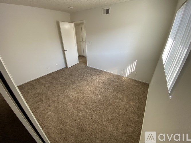 A room with carpeted floor and a doorway leading to another room.