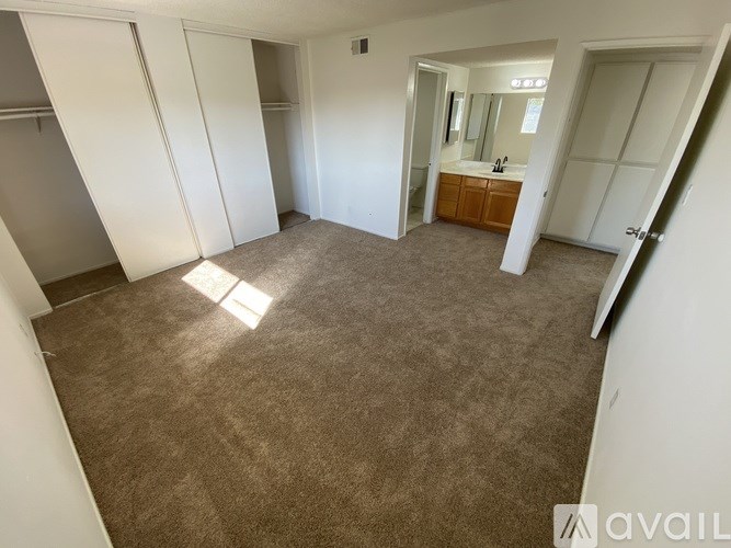 A carpeted room with a doorway leading to another room.