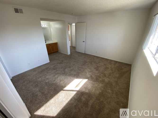A room with carpeted floor and a window letting in sunlight.