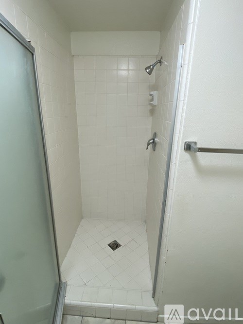 A white tiled bathroom with a glass door.