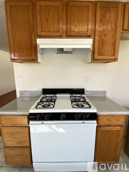 A white dishwasher and stove top oven with black knobs and handles.