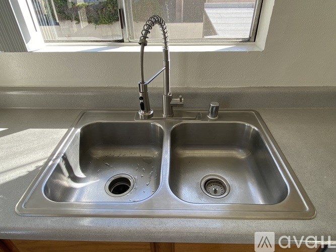 A double sink stainless steel kitchen sink with a faucet.