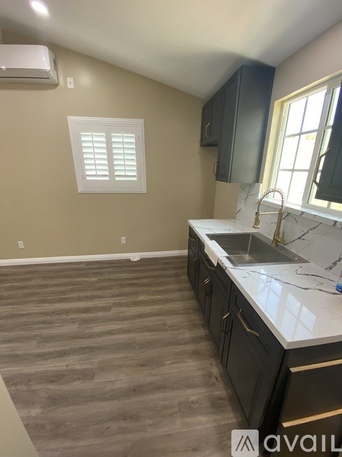 A kitchen with a sink, cabinets, and a window.