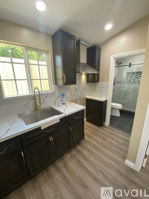 A kitchen with black cabinets and a marble countertop.