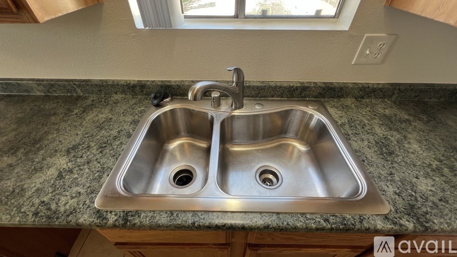 A double sink in a kitchen with granite countertop.