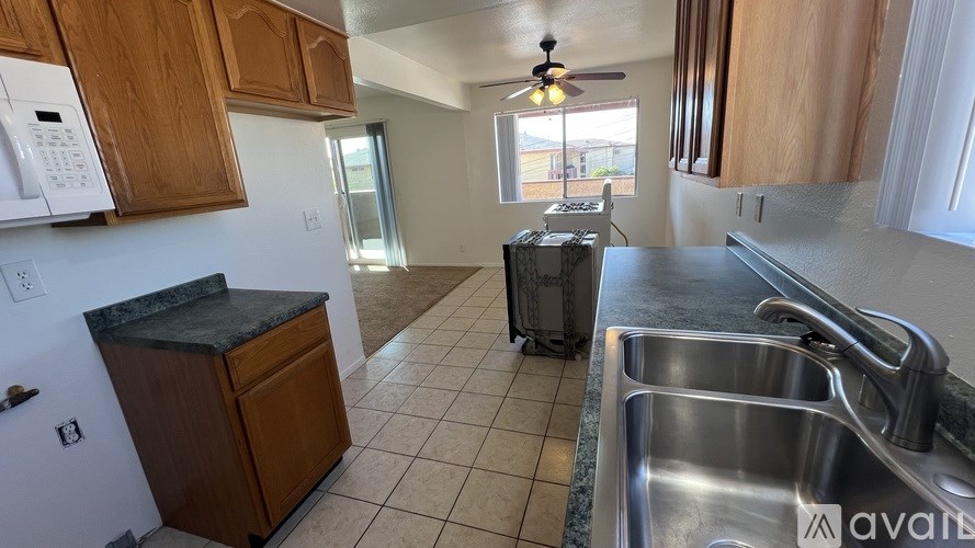 A kitchen with a white fridge, wooden cabinets, and a silver sink.