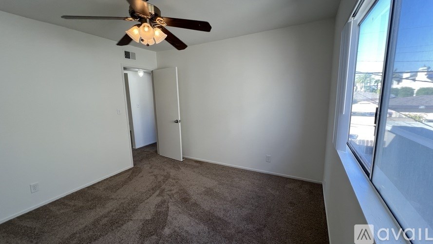 A room with a ceiling fan and carpeted floor.