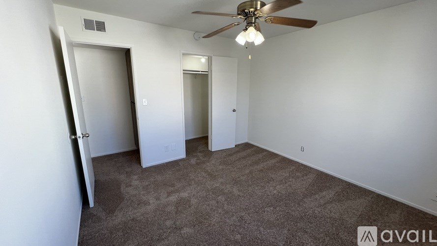 A room with a ceiling fan and carpeted floor.