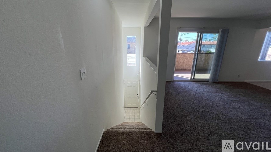 A hallway with a carpeted floor and a door leading to another room.