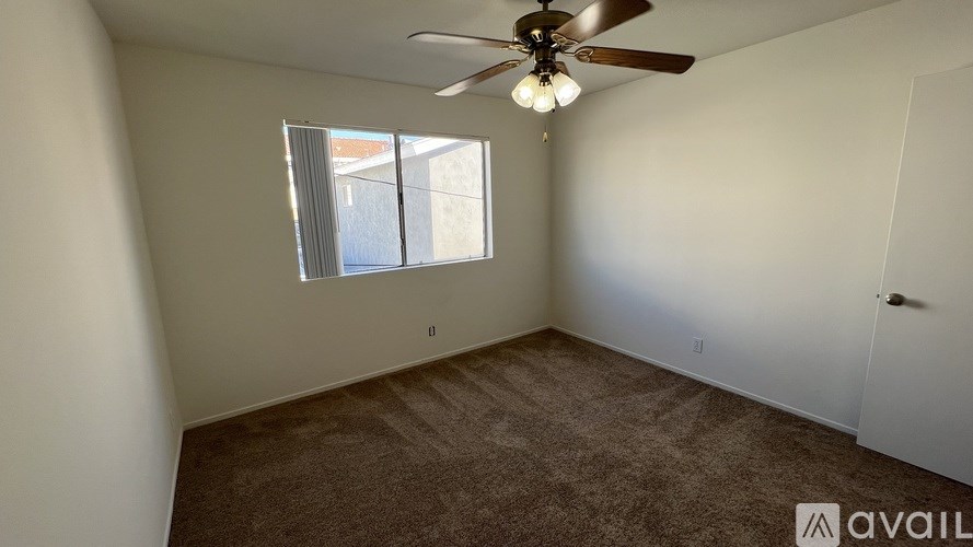 A room with a ceiling fan and carpeted floor.