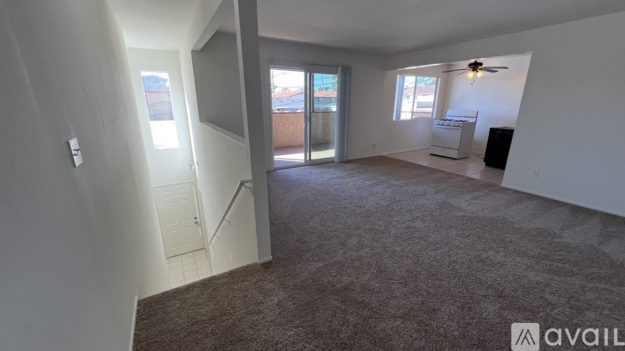 A room with a carpeted floor and a ceiling fan.