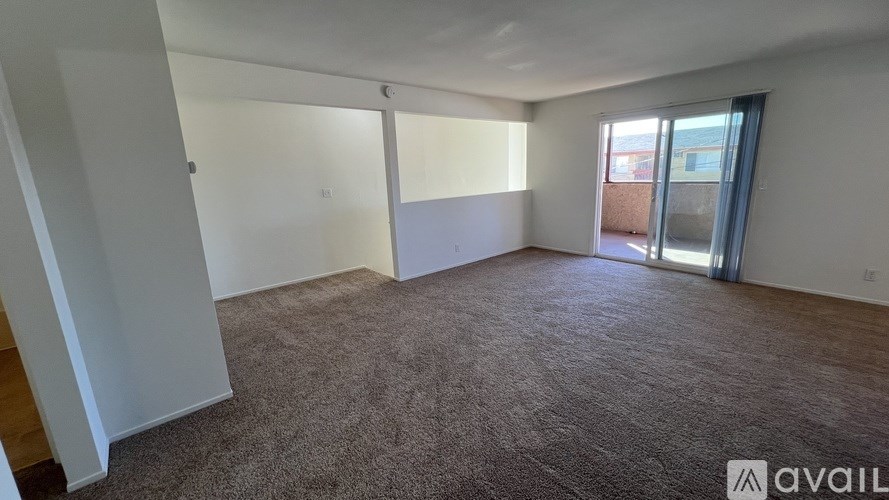 A room with carpeted floor and a door leading outside.