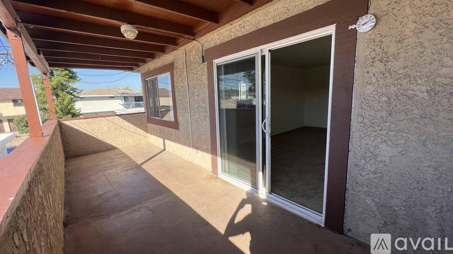 A patio area with a sliding glass door and a wooden pergola.