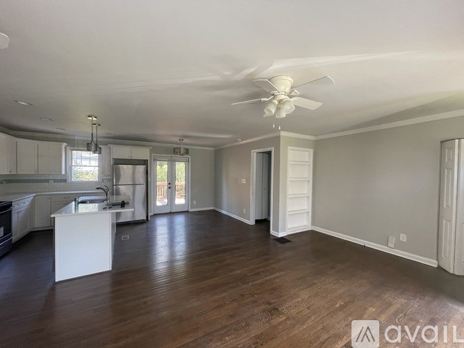 A spacious living room with a ceiling fan and hardwood floors.