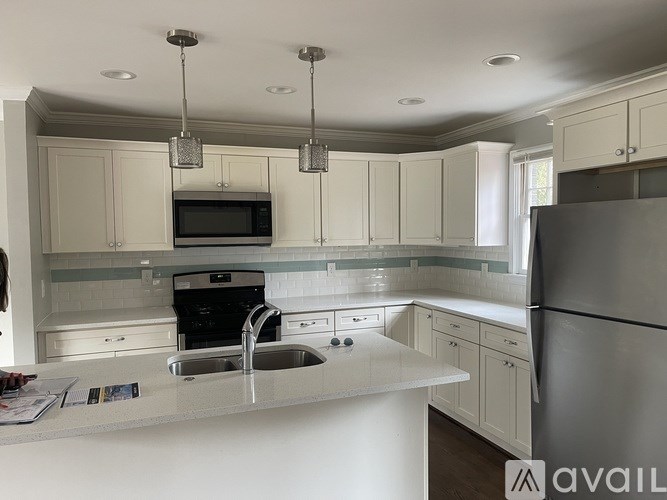 A kitchen with white cabinets and a stainless steel refrigerator.