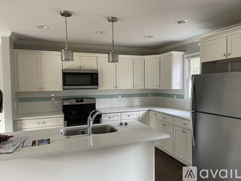 A kitchen with white cabinets and a stainless steel refrigerator.