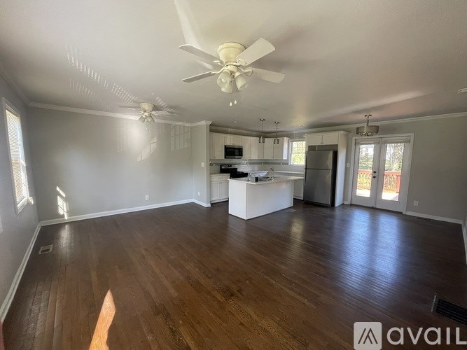 A spacious room with a ceiling fan and wooden flooring.