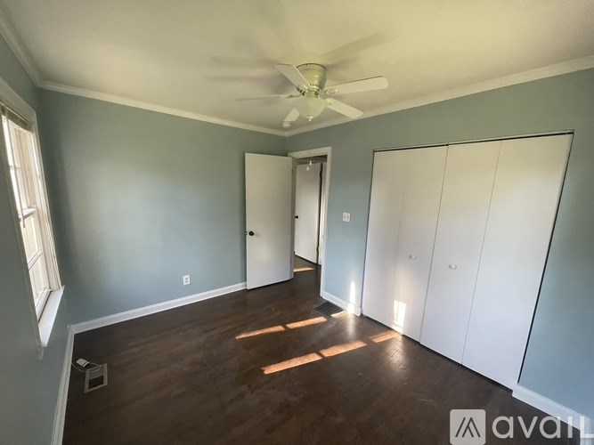 A room with a ceiling fan and wooden floors.