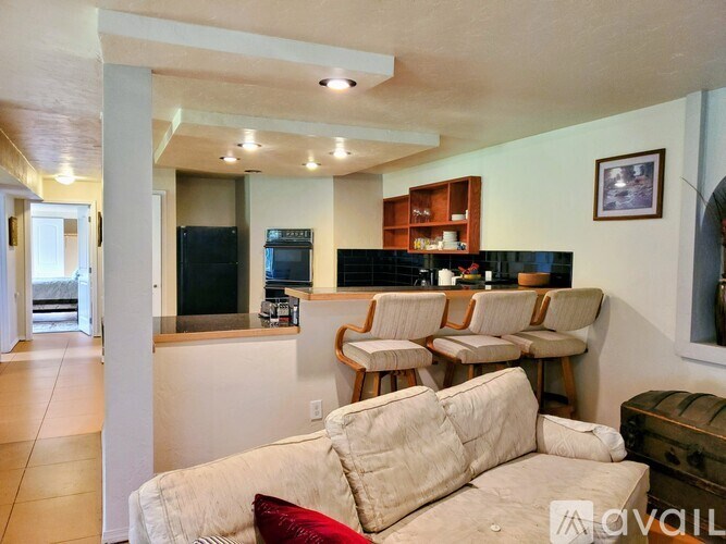 A living room with a couch, chairs, and a kitchen area in the background.