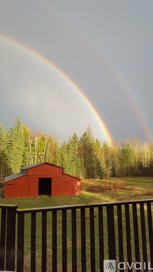 A red barn with a rainbow in the background.