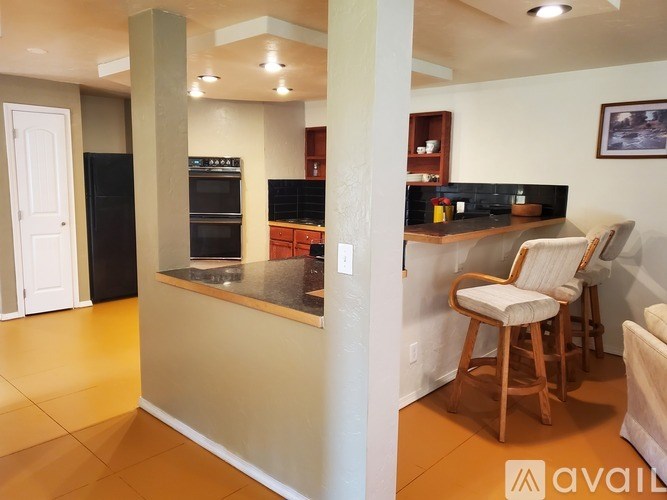 A kitchen with a black refrigerator and a wooden chair.