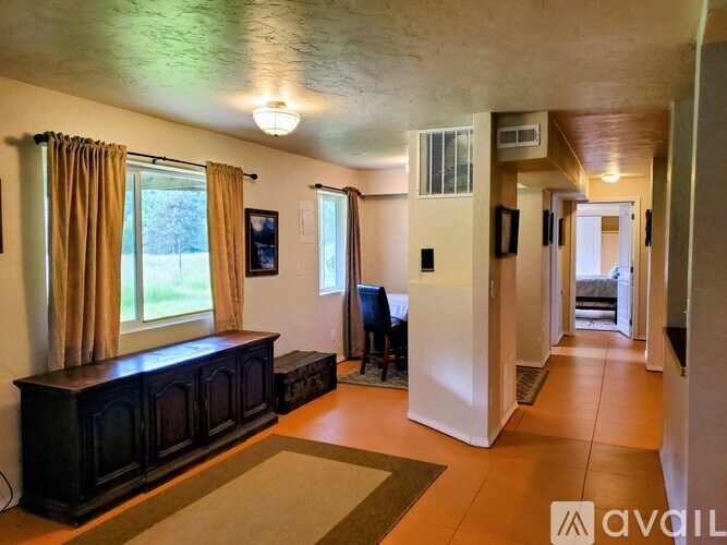 A living room with a brown sofa and a window with curtains.