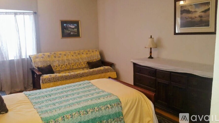 A bedroom with a bed, a couch, and a nightstand.