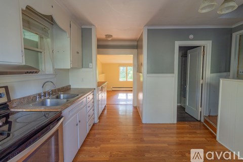 A kitchen with wooden floors and white cabinets.