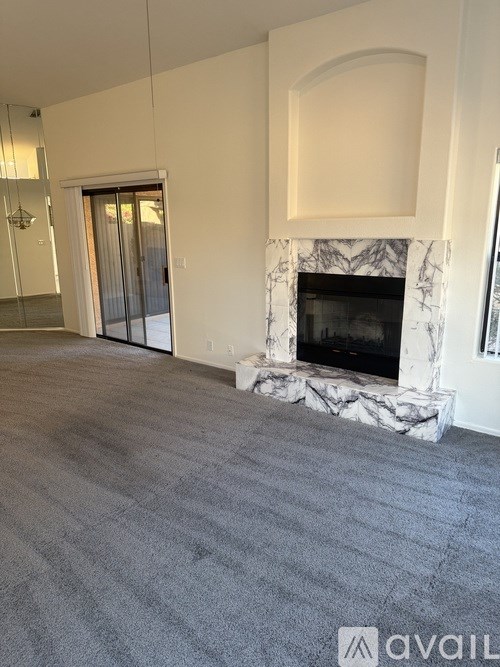A living room with a fireplace and grey carpet.