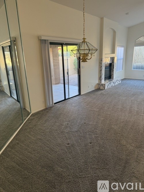 A carpeted room with a chandelier and a sliding glass door.