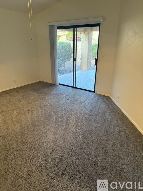 A room with a carpeted floor and a sliding glass door leading outside.
