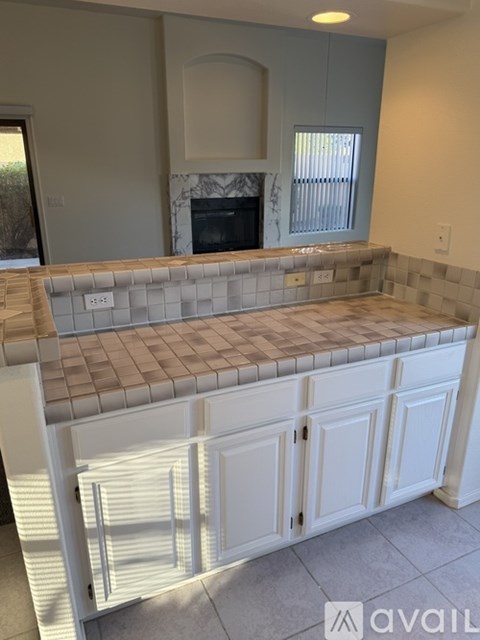 A kitchen with a tiled counter top and white cabinets.