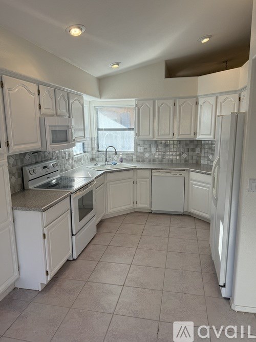 A kitchen with white cabinets and appliances.