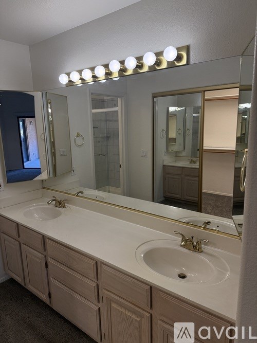 A bathroom with a vanity and a mirror with lights above it.
