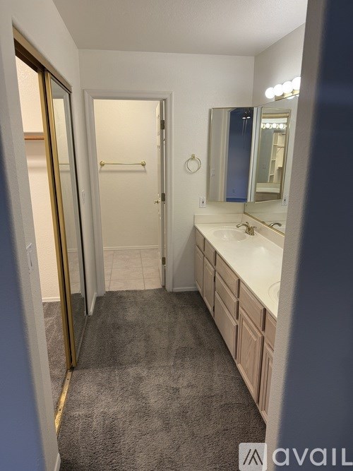A bathroom with a sink, mirror, and a carpeted floor.