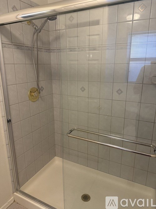 A shower with a glass door and a white tub.