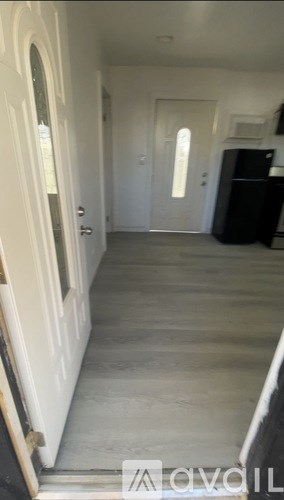 A hallway with a white door and a black refrigerator.