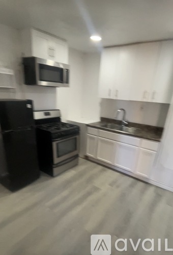 A kitchen with black appliances and white cabinets.
