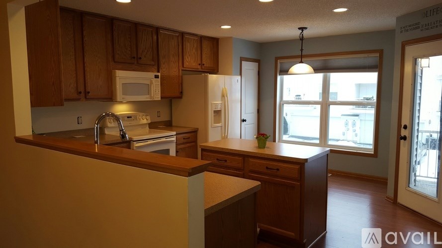 A kitchen with wooden cabinets and a countertop with a sink and a dishwasher.
