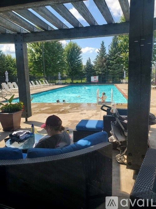 A person is sitting by a pool with a view of the pool and trees.