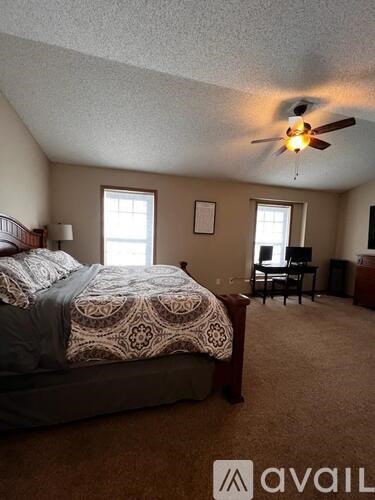 A bedroom with a bed, a ceiling fan, and a small table.