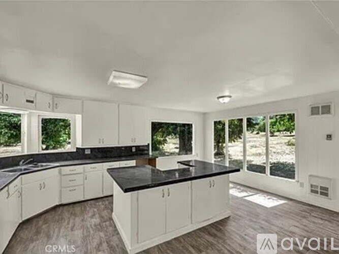 A kitchen with white cabinets and black countertops is available.